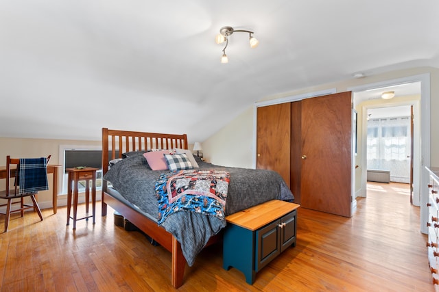 bedroom featuring a closet, lofted ceiling, and light wood finished floors