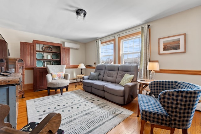 living room with a baseboard heating unit, an AC wall unit, and light wood finished floors