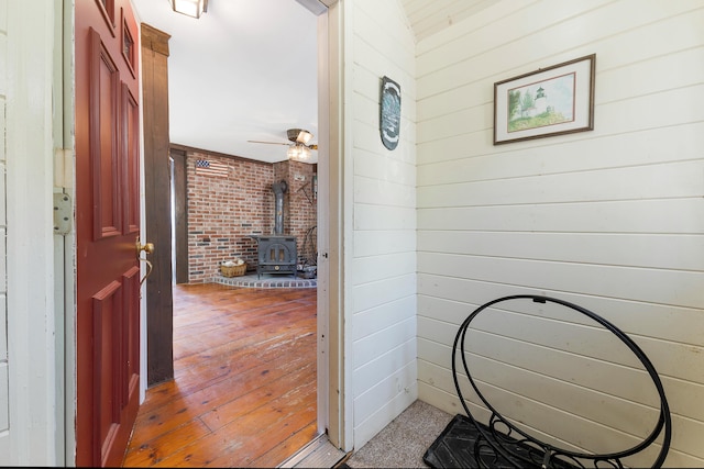 44 Periwinkle Ln, Phippsburg, ME 04562 - interior space featuring wooden walls, brick wall, a wood stove, and hardwood / wood-style flooring