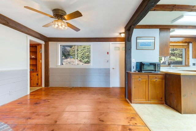 44 Periwinkle Ln, Phippsburg, ME 04562 - kitchen featuring brown cabinets, stainless steel microwave, light wood-style floors, wainscoting, and ceiling fan