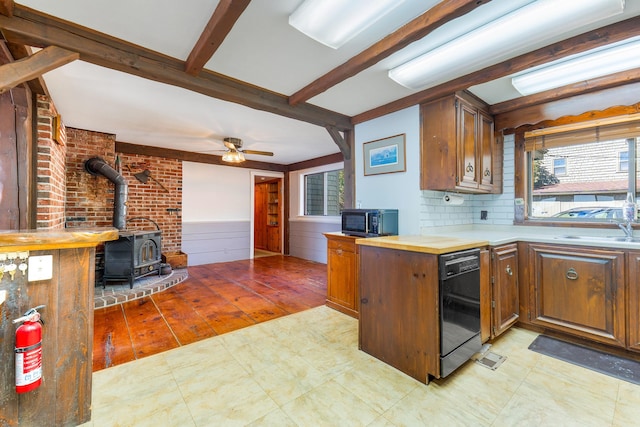 44 Periwinkle Ln, Phippsburg, ME 04562 - kitchen featuring a wainscoted wall, beam ceiling, a wood stove, a sink, and black appliances