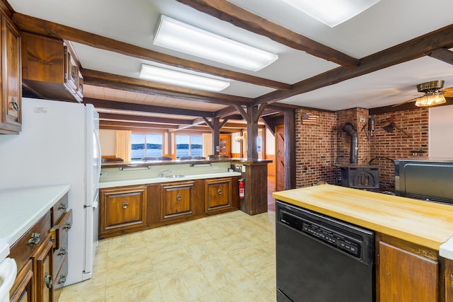 44 Periwinkle Ln, Phippsburg, ME 04562 - kitchen featuring beam ceiling, wood counters, black dishwasher, brick wall, and a wood stove