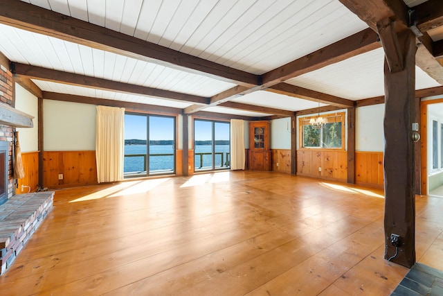 44 Periwinkle Ln, Phippsburg, ME 04562 - unfurnished living room with beamed ceiling, wainscoting, and a healthy amount of sunlight
