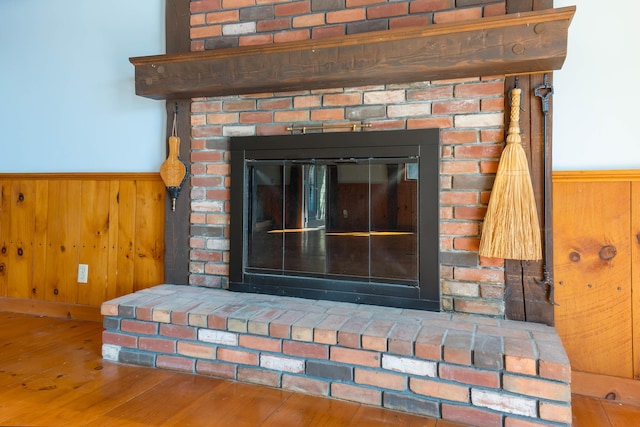 44 Periwinkle Ln, Phippsburg, ME 04562 - details with wooden walls, wainscoting, a glass covered fireplace, and wood finished floors