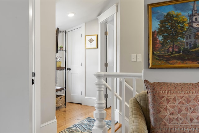 corridor featuring an upstairs landing and wood finished floors