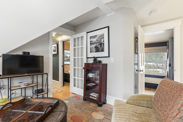 living room featuring french doors, baseboards, beamed ceiling, and wood finished floors