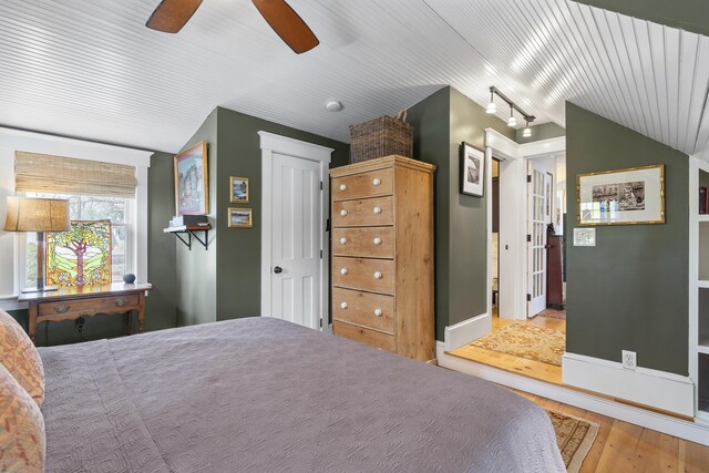 bedroom with ceiling fan, lofted ceiling, and wood finished floors