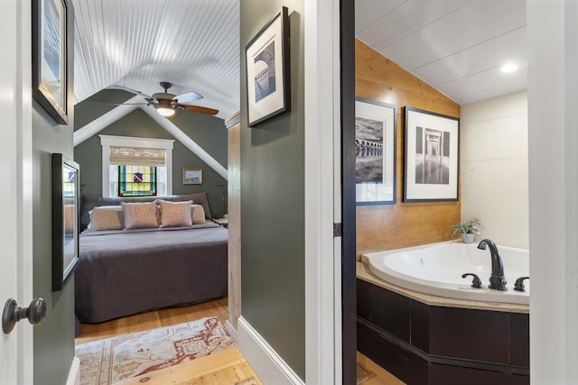 bathroom with a garden tub, ensuite bathroom, wood finished floors, ceiling fan, and vaulted ceiling