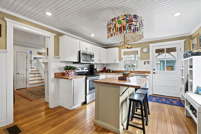 kitchen featuring visible vents, light wood-style flooring, ornamental molding, appliances with stainless steel finishes, and butcher block counters