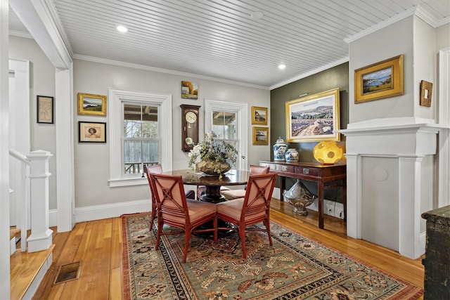 dining room featuring visible vents, light wood-style flooring, baseboards, and ornamental molding