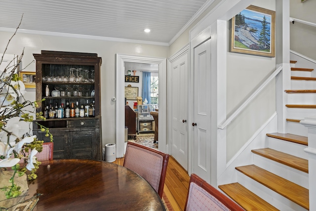 bar with stairs, crown molding, a dry bar, and wood finished floors