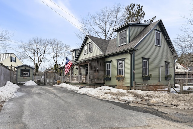 view of side of home with roof with shingles and fence