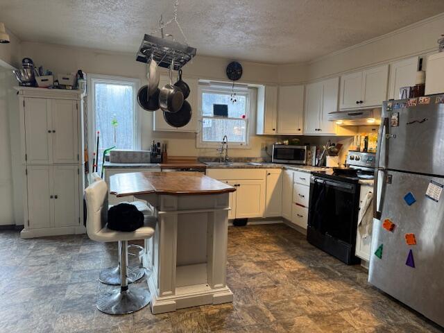 kitchen with a kitchen island, a sink, stainless steel appliances, under cabinet range hood, and white cabinetry