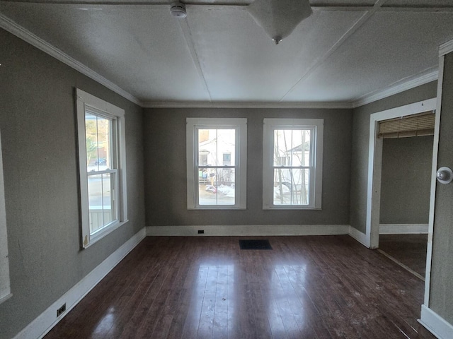 spare room with dark wood-type flooring, a healthy amount of sunlight, visible vents, and ornamental molding