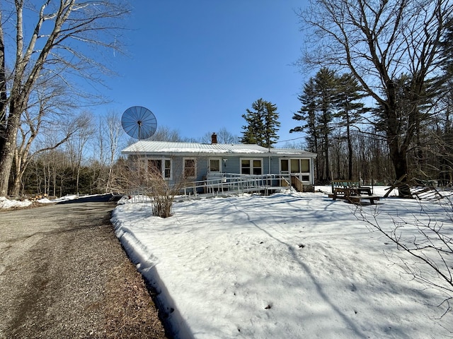 view of front of house featuring metal roof, a wooden deck, and a chimney