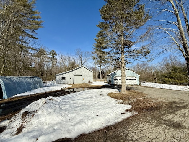 yard covered in snow featuring an outdoor structure and a garage