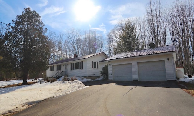 ranch-style home with a chimney, metal roof, and a garage