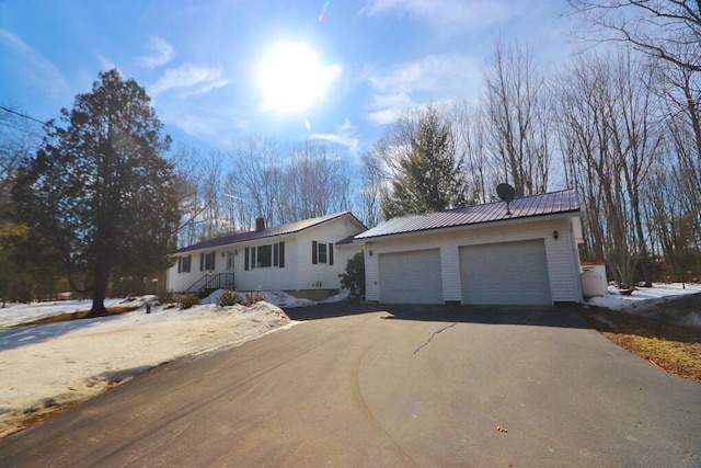 ranch-style home with a garage, metal roof, and a chimney