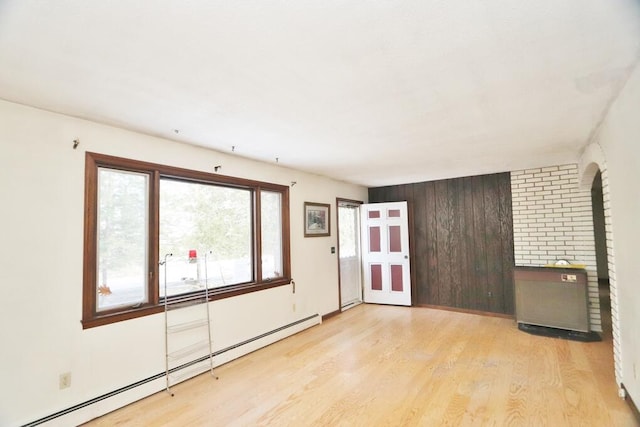 spare room featuring baseboard heating and wood finished floors