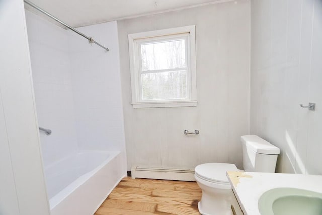 full bathroom with a baseboard heating unit, toilet, vanity, wood finished floors, and washtub / shower combination