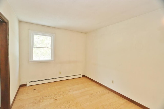 unfurnished room featuring baseboards, a baseboard heating unit, and light wood-style floors