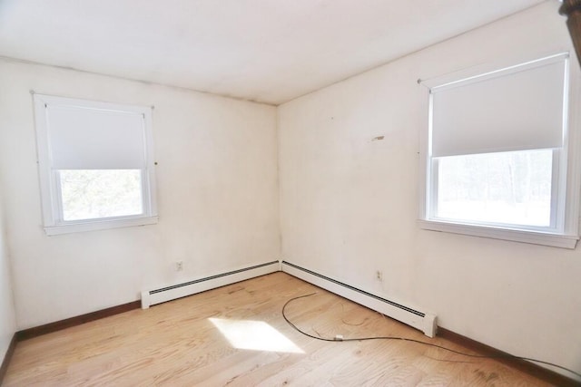 empty room featuring wood finished floors, baseboards, and a baseboard radiator