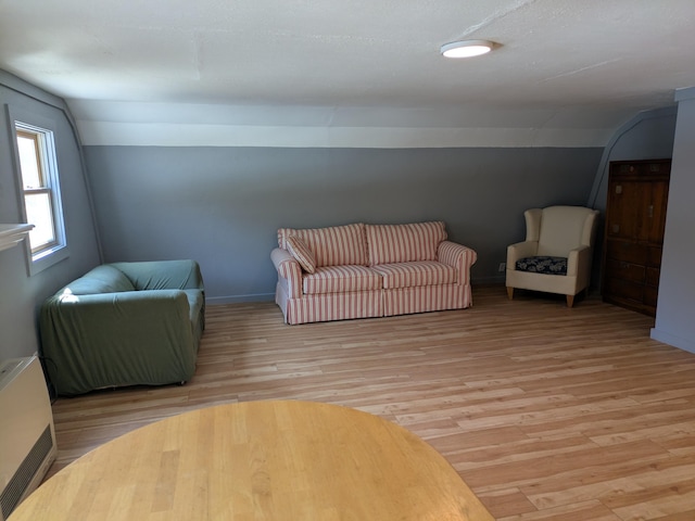 living room featuring lofted ceiling, baseboards, and light wood-type flooring