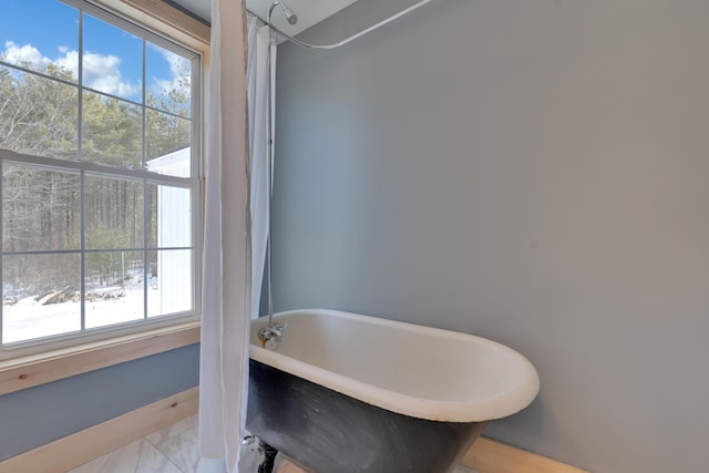 full bath with a soaking tub and marble finish floor