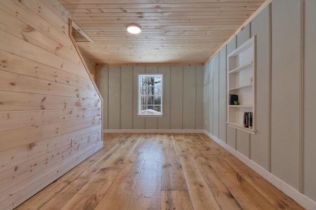 unfurnished room featuring wooden ceiling, light wood-style flooring, and built in shelves