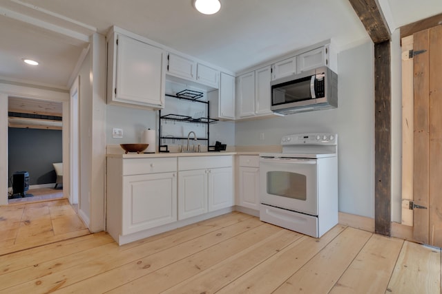 kitchen featuring light wood finished floors, stainless steel microwave, electric stove, and a sink