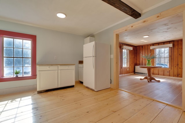 kitchen with radiator, freestanding refrigerator, white cabinets, beamed ceiling, and light wood-type flooring