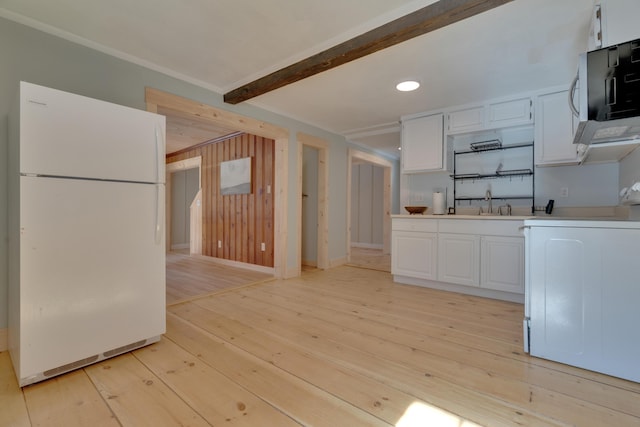 kitchen featuring light wood-style flooring, freestanding refrigerator, white cabinets, stainless steel microwave, and range