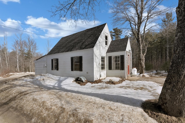 snow covered property with a shingled roof