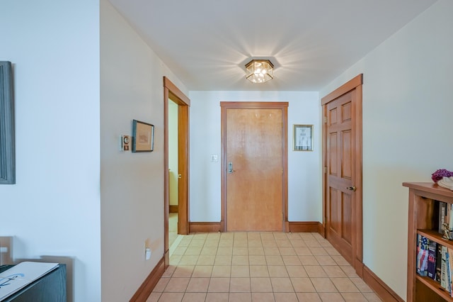 hall featuring light tile patterned flooring and baseboards