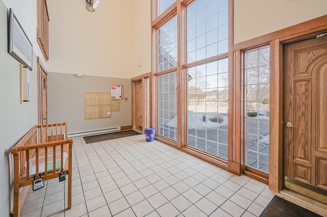 foyer with a baseboard radiator, a high ceiling, and light tile patterned flooring