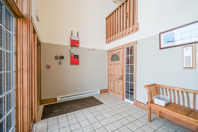 foyer entrance with light tile patterned flooring, baseboards, a towering ceiling, and a baseboard radiator