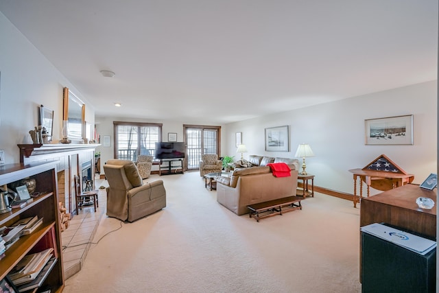 living room with a fireplace with raised hearth, baseboards, and light carpet