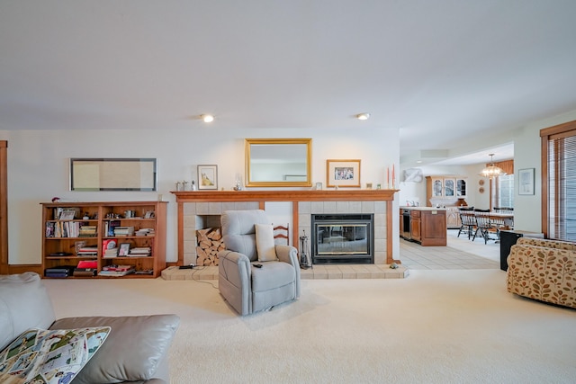 living room featuring light carpet, a chandelier, and a tile fireplace