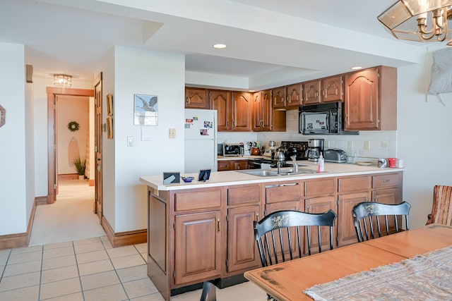 kitchen with backsplash, light countertops, black microwave, and freestanding refrigerator