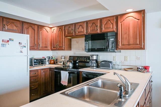 kitchen featuring decorative backsplash, black appliances, light countertops, and a sink