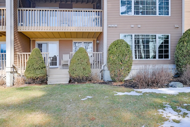 entrance to property featuring a balcony and a yard