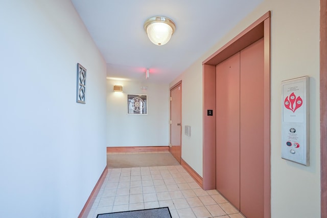 hallway featuring elevator, baseboards, and light tile patterned flooring