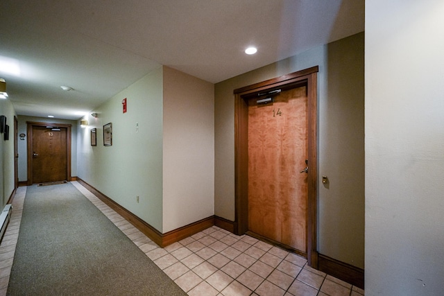 corridor with light tile patterned floors and baseboards