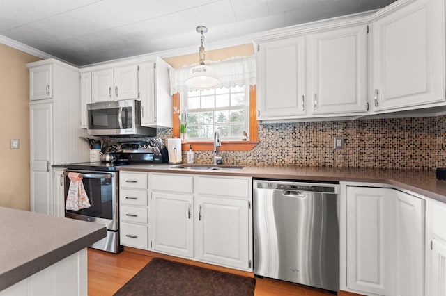 kitchen with a sink, appliances with stainless steel finishes, light wood-style flooring, and white cabinetry