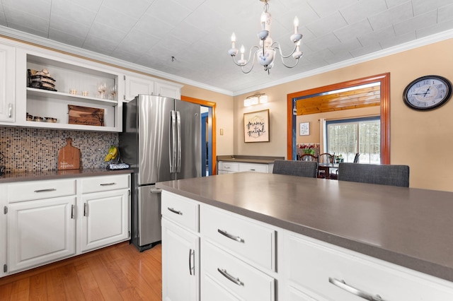 kitchen with dark countertops, freestanding refrigerator, and ornamental molding