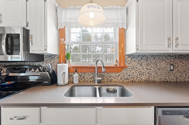 kitchen featuring a sink, stainless steel appliances, white cabinets, and decorative backsplash