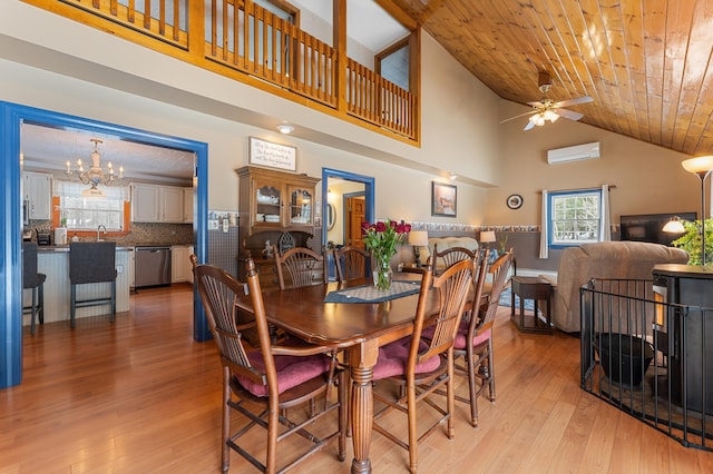 dining area featuring light wood finished floors, a wall mounted AC, wood ceiling, a towering ceiling, and ceiling fan with notable chandelier