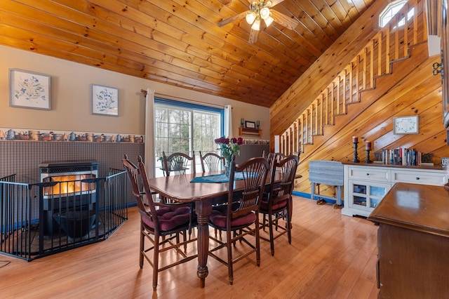 dining space featuring wooden walls, wood ceiling, stairs, vaulted ceiling, and wood finished floors