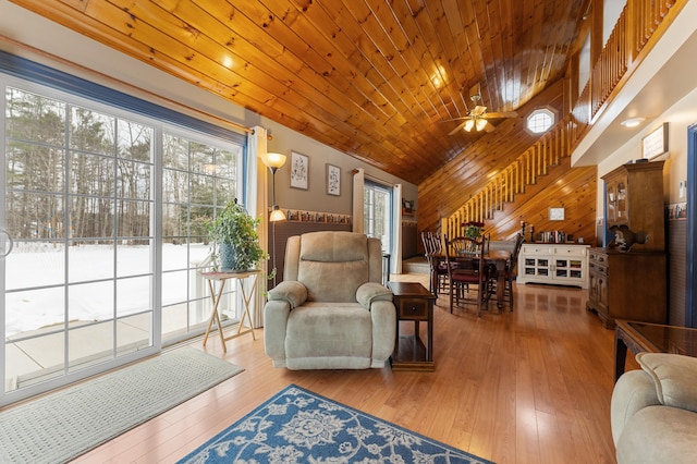 sitting room featuring hardwood / wood-style floors, wooden walls, a ceiling fan, stairs, and wooden ceiling