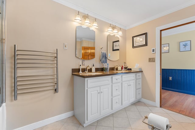 bathroom with baseboards, radiator heating unit, ornamental molding, a sink, and tile patterned floors